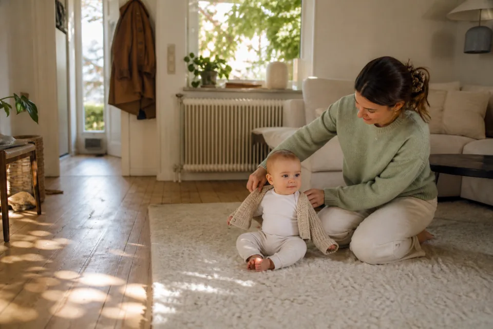 A parent opening a baby's cardigan in a warm room after a neck check
