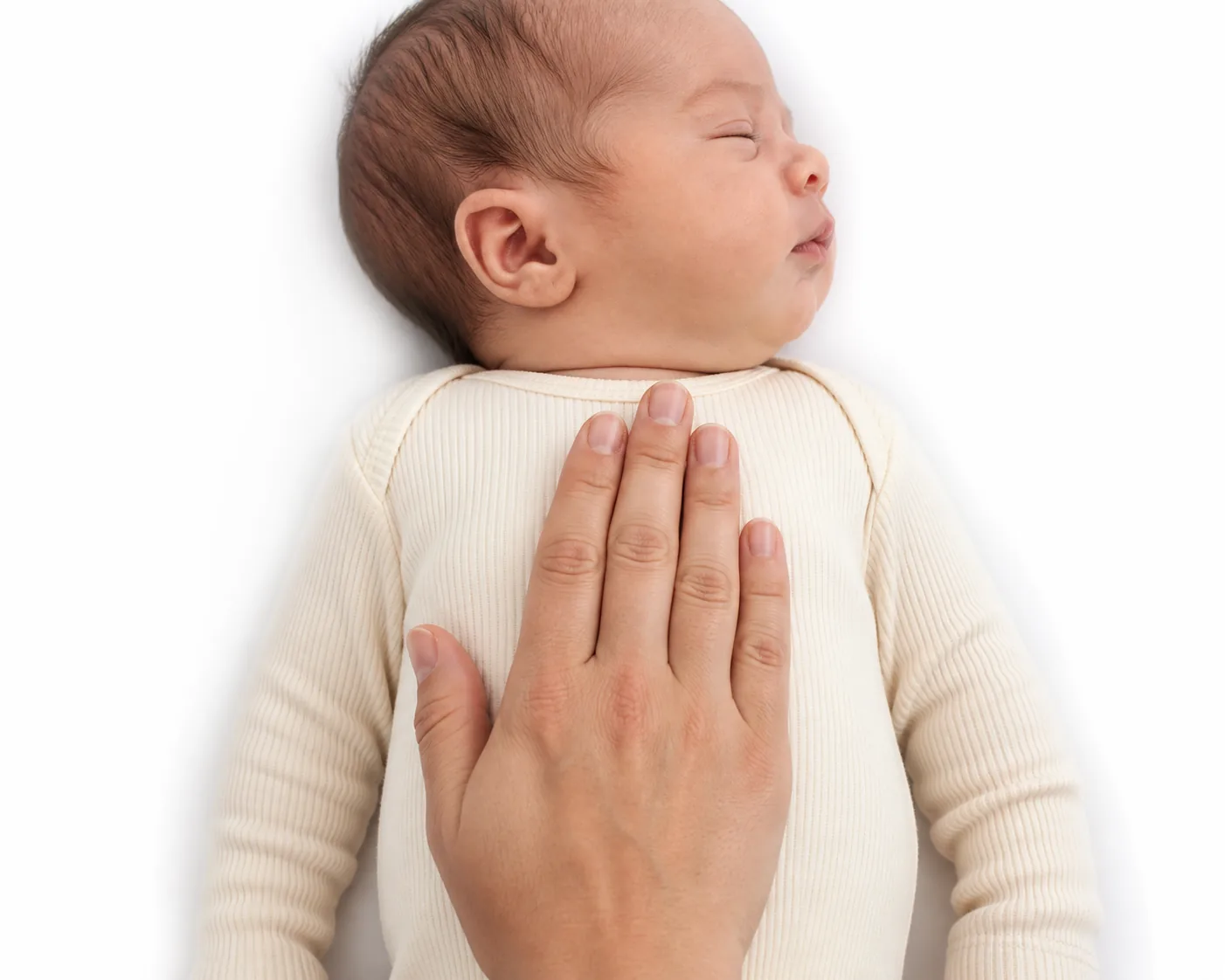 An adult hand resting flat on the upper chest of a newborn in a cream bodysuit