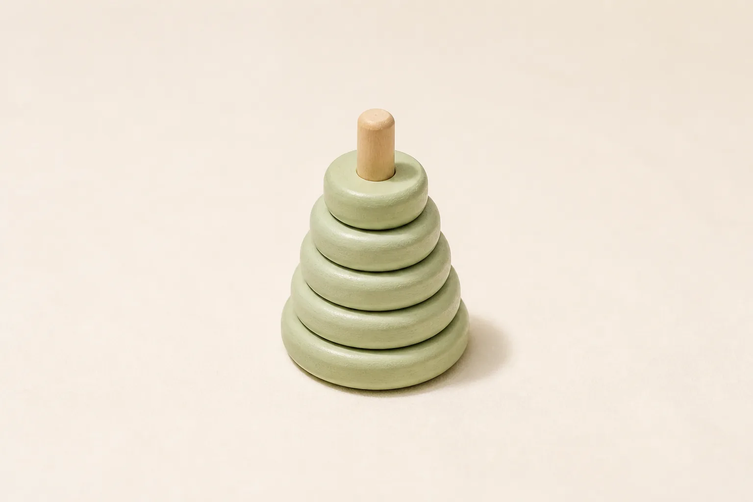 A pale sage wooden toy casting a short midday shadow